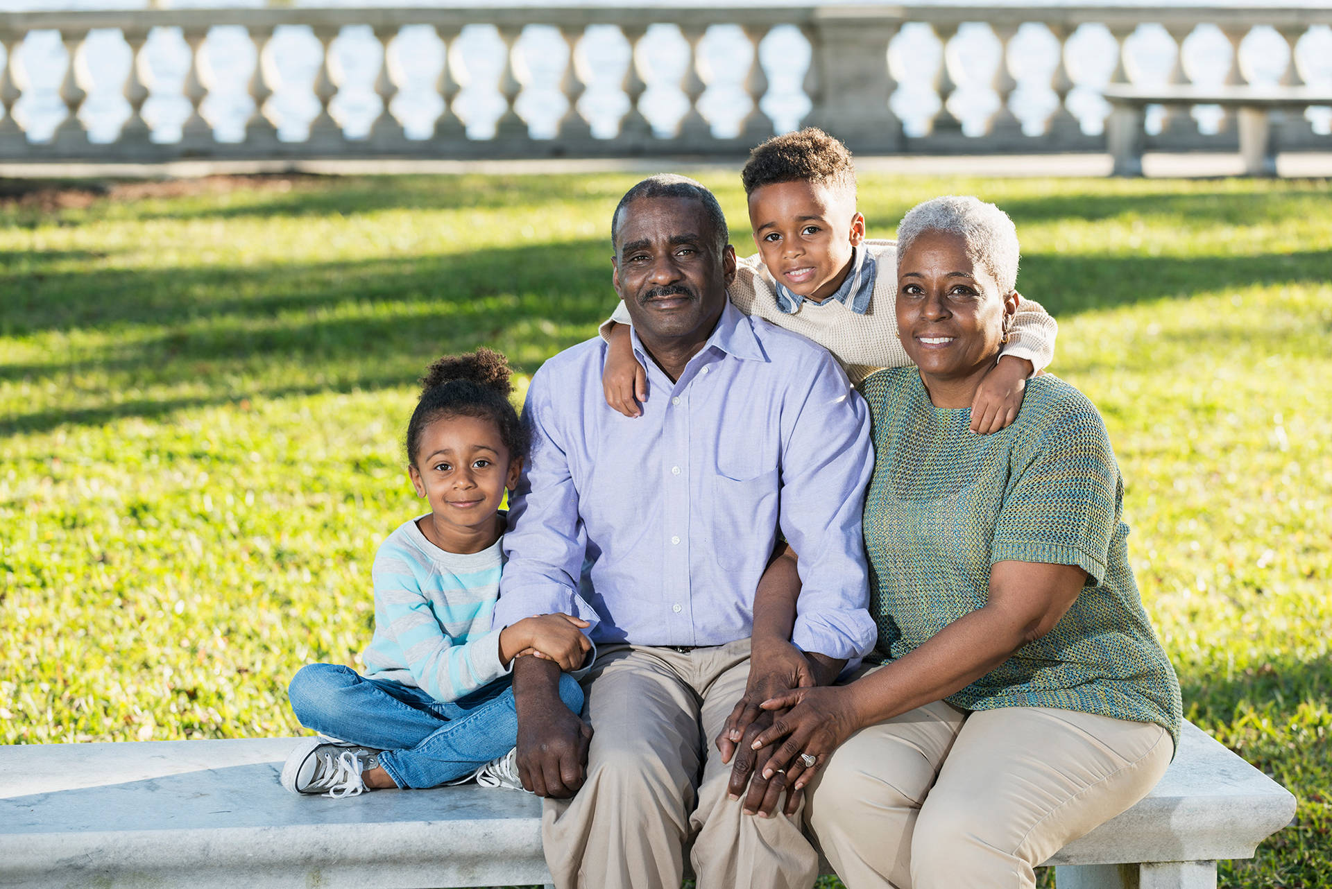 African-American grandparents with young grandson and granddaughter sitting on bench